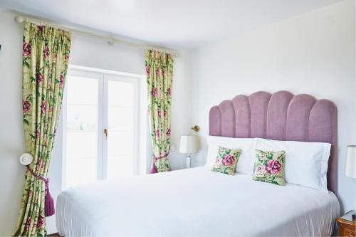 a bedroom with a large white bed with a pink headboard at Solar Alvura Boutique Hotel in Moncarapacho