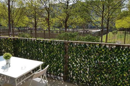 una cerca con una mesa y sillas junto a un seto en Le petit Kaplan-studio cosy avec terrasse-parking en Lyon