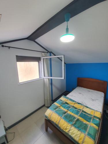 um pequeno quarto com uma cama e uma janela em Enjoy the Island - Rua do Negrão em Ponta Delgada