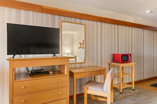 a hotel room with a television and a desk and a mirror at Harbor Lite Lodge in Fort Bragg