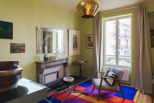 uma sala de estar com lareira e uma cadeira em Le Grand Maulnes em Paris