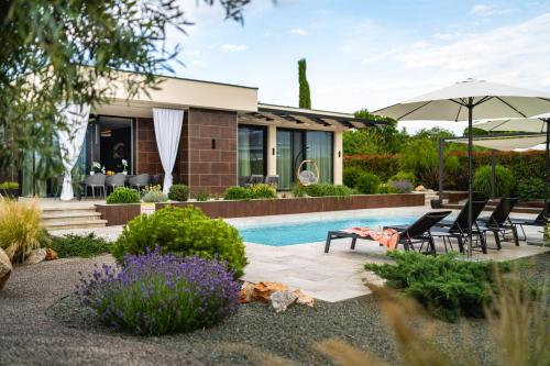 a house with a pool and chairs and an umbrella at Villa Blumarine in Krk