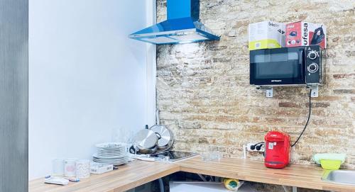 a kitchen with a counter with a tv on a brick wall at CAMP NOU & FiRA BUSINESS LOFTS in Barcelona