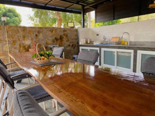 a large wooden table with chairs and a kitchen at Arom Pool Villa Pattaya 1 in Na Jomtien