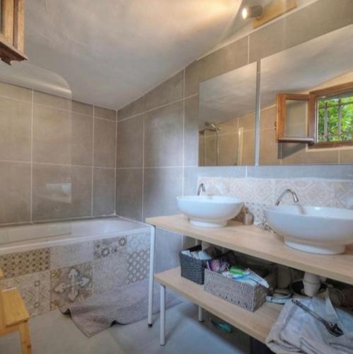 une salle de bain avec deux lavabos et un grand miroir dans l'établissement Maison de campagne calme jacuzzi, à Grasse