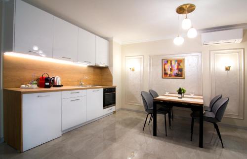 a kitchen with white cabinets and a table with chairs at Odrys Apartments in Plovdiv