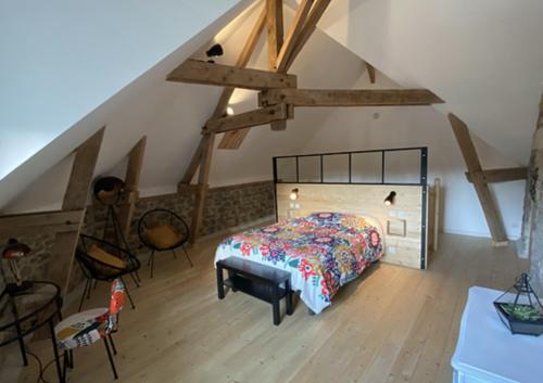 een slaapkamer met een bed en stoelen op een zolder bij Duplex accès jacuzzi illimité Z in Villedieu-les-Poëles
