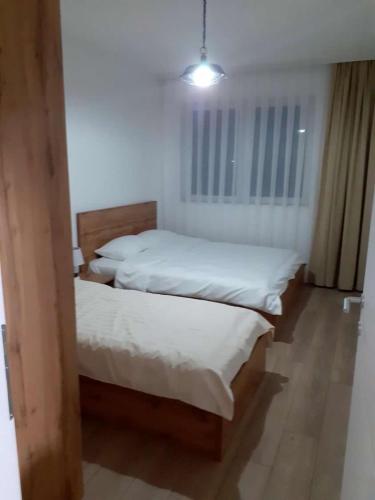two beds in a room with white sheets at Banesa ne qender te Pejes in Peje