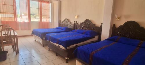 een slaapkamer met drie bedden met blauwe lakens erop bij Hotel Chaparral in Panajachel