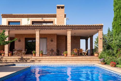 a villa with a swimming pool in front of a house at Villa Marín Toledo in Las Nieves