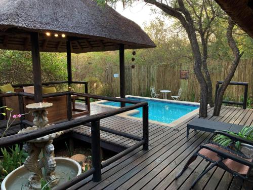 a deck with a umbrella and a swimming pool at Hoedspruit Raptors Lodge N16 in Hoedspruit