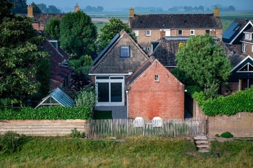 a red brick house with a fence in front of it at Dyk hûs in Moddergat