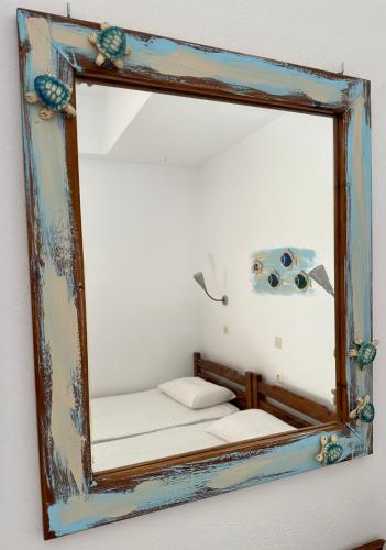 a mirror hanging on a wall with a bed at BONATSA ROOMS in Palaiochóra