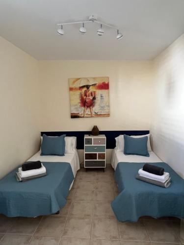 AjuyにあるVivienda Vacacional Casa Olaのベッド2台が備わる客室で、壁には絵画が飾られています。