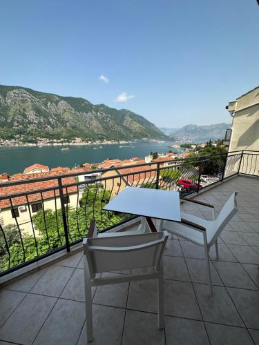 een tafel en 2 stoelen op een balkon met uitzicht op het water bij Point of View in Kotor