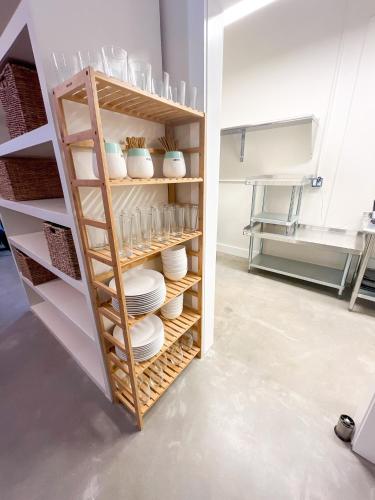 a kitchen with a shelf with plates and bowls at ITH Santa Barbara Surf Hostel in Santa Barbara