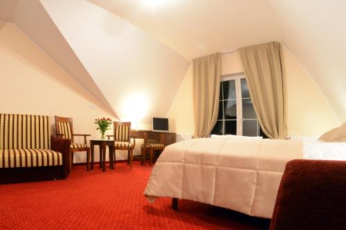 a hotel room with a bed and a desk and chair at Dworek Jamneński in Łazy