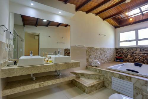 uma casa de banho com 2 lavatórios e uma banheira em Pousada Famiglia Bartho em Espirito Santo Do Pinhal