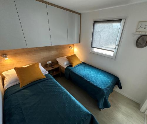 two beds in a small room with a window at Mobile home Mare Blu in Rovanjska