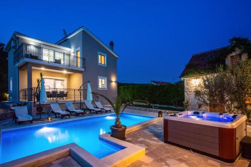 a swimming pool in front of a house at night at VIP Luxury villa with a heated pool and jacuzzi-Granny's Gold in Lovreć