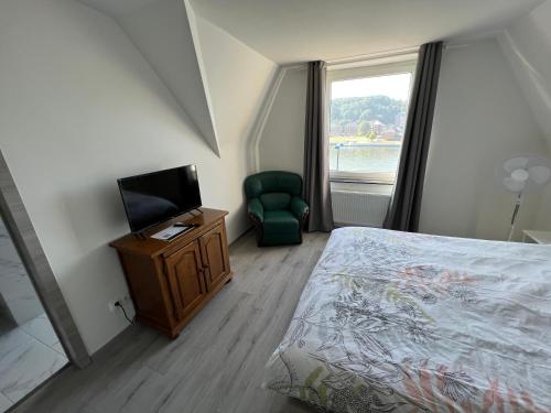 a bedroom with a bed and a television and a chair at Riverbank Guest House in Namur