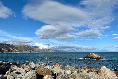 a pile of rocks in the water with a rock in the ocean at BONATSA ROOMS in Palaiochóra