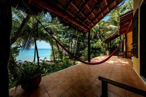 a porch of a house with a hammock overlooking the ocean at Hotel Rancho Encantado in Bacalar