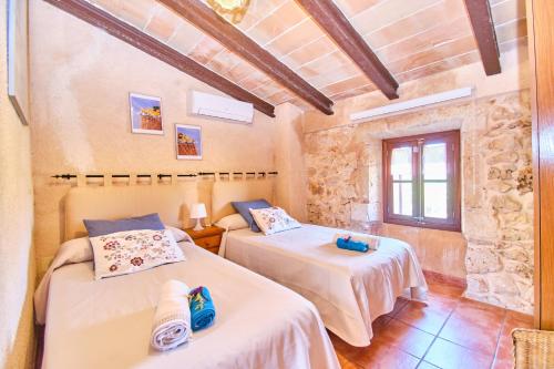2 camas en una habitación con una pared de piedra en Villa Rural Son Pou, en Sa Pobla