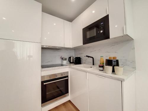 une cuisine blanche avec des armoires blanches et un micro-ondes dans l'établissement Nestor&Jeeves - COEUR RIVIERA - City Center - Near Beach, à Nice