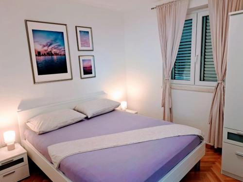 1 dormitorio con 1 cama grande con sábanas moradas en Apartman Nina, en Omiš