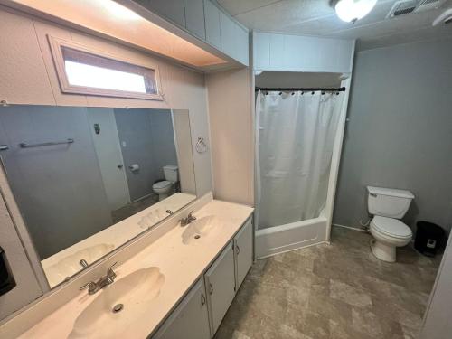 La salle de bains est pourvue de 2 lavabos, de toilettes et d'un miroir. dans l'établissement Preciosa casa para 10 personas, à Mexicali