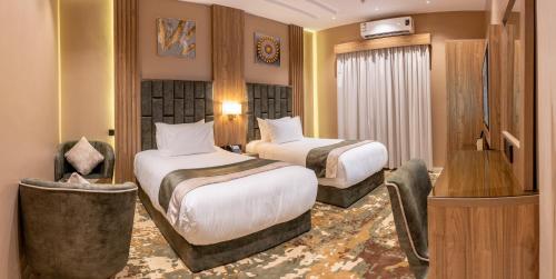 a hotel room with two beds and a chair at Mostagr Serviced Apartments - Yasmine in Hail