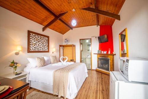 a bedroom with a white bed and a fireplace at Pousada Nascer da Lua in Monte Verde