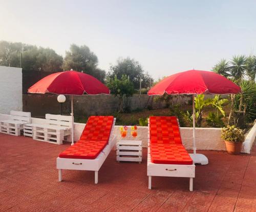 2 sedie e ombrelloni rossi e bianchi su un patio di Casetta del sole a Lampedusa