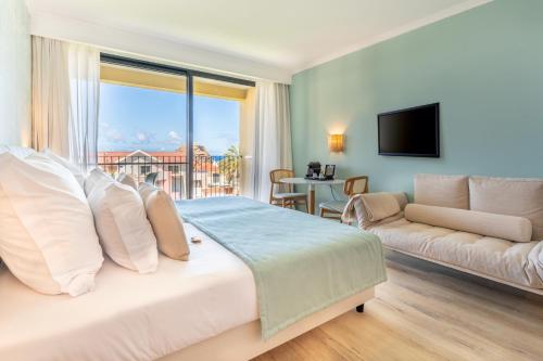 Studios by Aqua Natura Hotels في بورتو مونيز: غرفة نوم بسرير كبير وأريكة