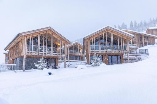 eine Gruppe von Holzgebäuden im Schnee in der Unterkunft Bergresort Hauser Kaibling by ALPS RESORTS in Haus im Ennstal