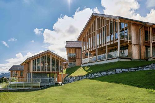 two large wooden buildings on top of a green field at Bergresort Hauser Kaibling by ALPS RESORTS in Haus im Ennstal