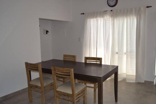 a dining room table with four chairs and a clock at Almirante Brown 235 , Dpto 5 in San Martín