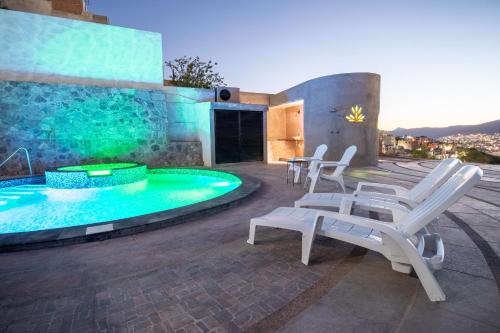a patio with white chairs and a swimming pool at Casa de Tillie in Guanajuato