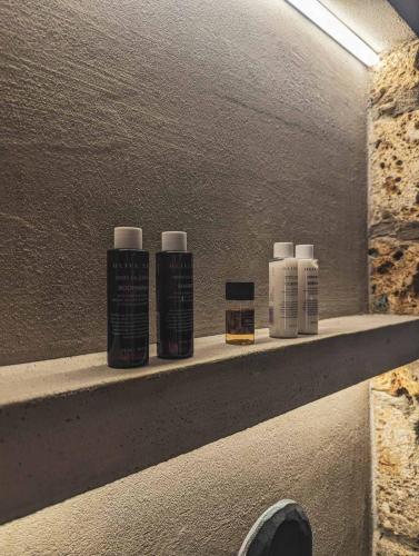 a shelf with four bottles of hair products on it at Three Dots Boutique Suites in Soúlion