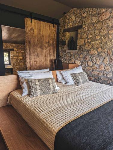 a bedroom with a large bed with a stone wall at Three Dots Boutique Suites in Soúlion