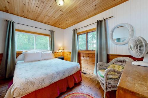 1 dormitorio con cama, mesa y espejo en Leavitt Bay Shores, en Ossipee