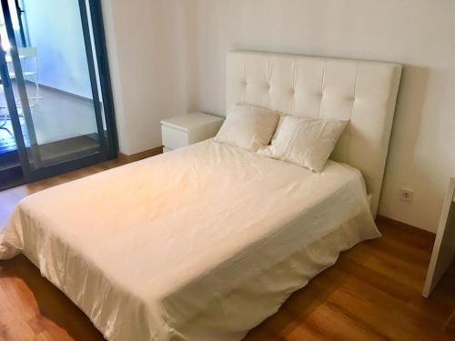 een slaapkamer met een groot bed met witte lakens en kussens bij Lisbon South Bay Apartment with terrace in Almada