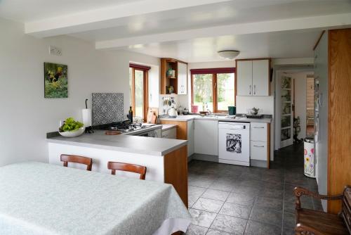 una cocina con armarios blancos y una mesa con sillas. en Meadow Cottage, en Belmullet