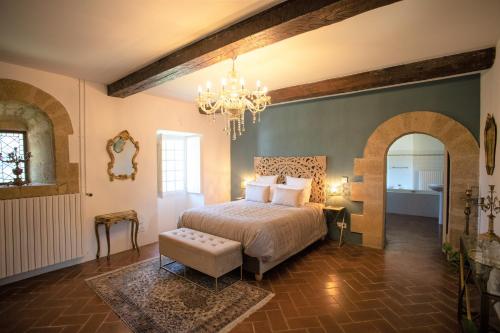 - une chambre avec un lit et un lustre dans l'établissement Château Saint-Pierre de Mejans, à Puyvert