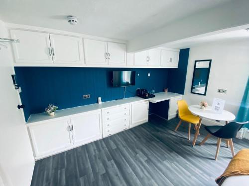 a kitchen with white cabinets and a table and a blue wall at Avalon Hotel in Brighton & Hove