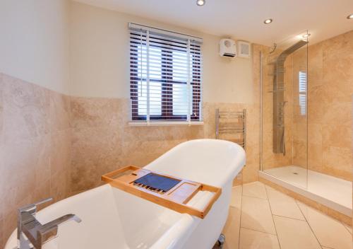 a bathroom with a white tub and a shower at Hawkeswade Barn in Ufford