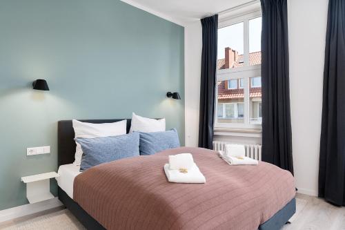 a bedroom with a large bed with two towels on it at FLATLIGHT: Hildesheim Angoulemeplatz in Hildesheim