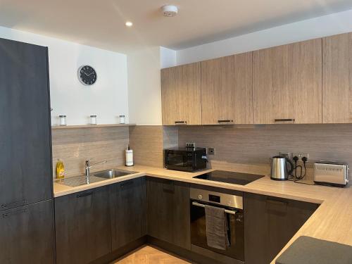 una cucina con armadi in legno, lavandino e forno a microonde di Modern City Centre Apartment a Birmingham