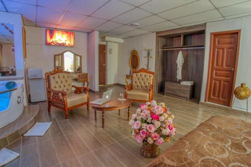 a living room with chairs and a table with flowers at Hotel Royalty in Riobamba